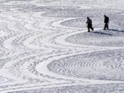 British artist Simon Beck, left, and a volunteer put the final touches on a geometrical snow drawing Jan. 7 on a frozen reservoir near Silverthorne, Colo. Beck says he hopes his art makes people more aware of the beauty of the environment.