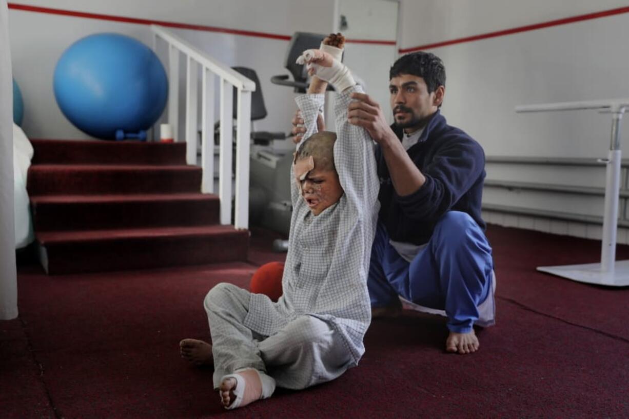 An Afghan physiotherapist helps 9-year-old Eimal, who has lost his right eye and several fingers on his hands in a land mine blast, stretch at Emergency Surgical Center for Civilian War Victims in Kabul, Afghanistan.