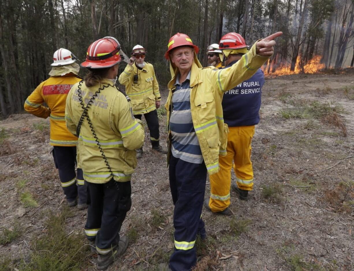 Doug Schutz, center, the Tomerong Rural Fire Service Captain, oversees a controlled burn Wednesday near Tomerong, Australia, set in an effort to contain a larger fire nearby.