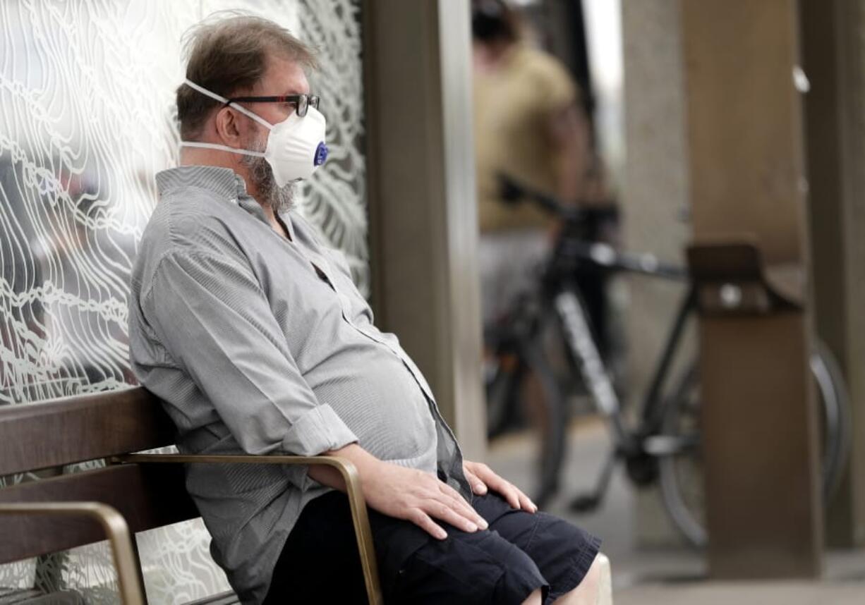 FILE - In this Jan. 2, 2020, file photo, a commuter wears a mask as smoke shrouds the Australian capital of Canberra, Australia. It&#039;s an unprecedented dilemma for Australians accustomed to blue skies and sunny days that has raised fears for the long-term health consequences if prolonged exposure to choking smoke becomes the new summer norm.