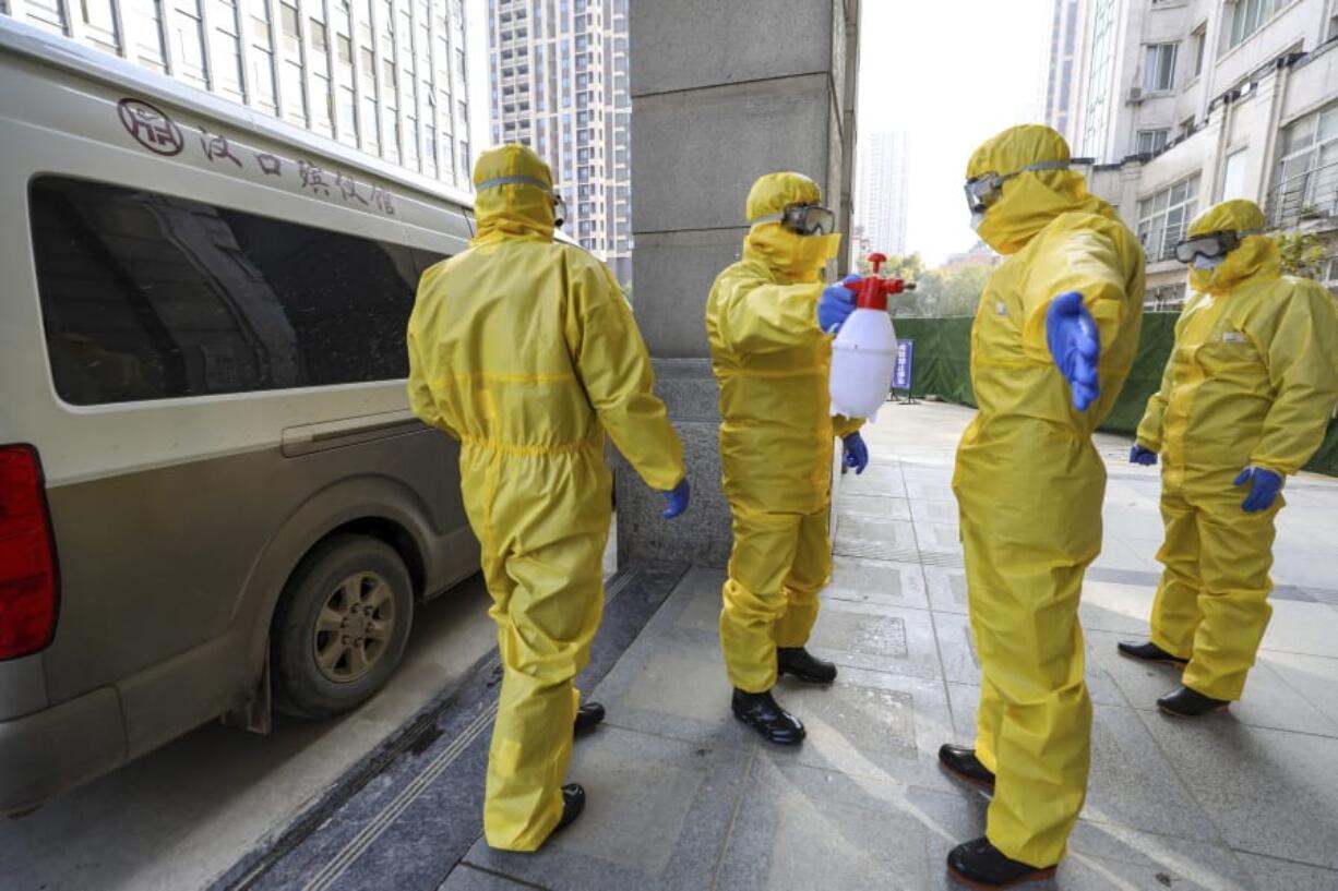 Funeral workers disinfect themselves after handling a virus victim in Wuhan in central China&#039;s Hubei Province, Thursday, Jan. 30, 2020. China counted 170 deaths from a new virus Thursday and more countries reported infections, including some spread locally, as foreign evacuees from China&#039;s worst-hit region returned home to medical observation and even isolation.