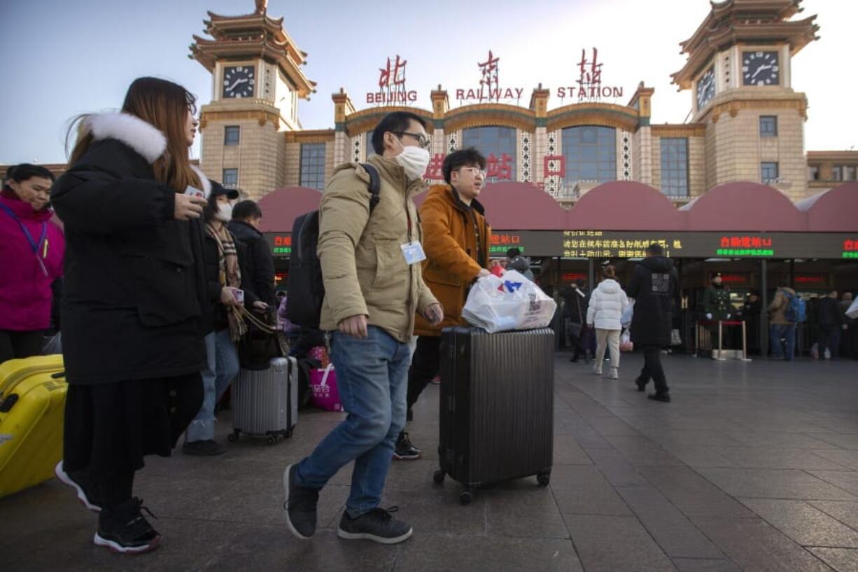 A traveler wears a face mask as he walks outside of the Beijing Railway Station in Beijing, Monday, Jan. 20, 2020. China reported Monday a sharp rise in the number of people infected with a new coronavirus, including the first cases in the capital. The outbreak coincides with the country&#039;s busiest travel period, as millions board trains and planes for the Lunar New Year holidays.