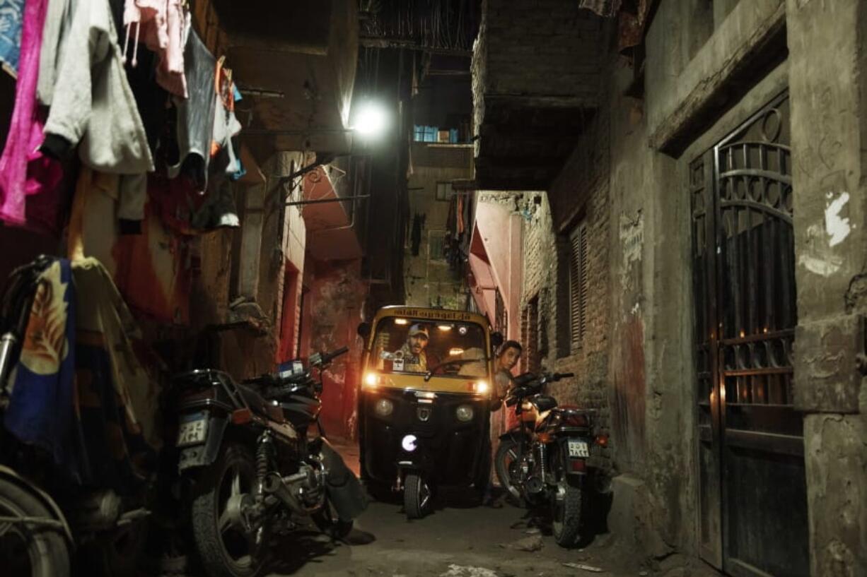 In this Nov. 19, 2019 photo, a driver tries to maneuver his tuk-tuk in a narrow alleyway of a slum in Cairo, Egypt. Motorized rickshaws known as tuk-tuks have ruled the streets of Cairo&#039;s slums for the past two decades hauling millions of Egyptians home every day. Now the government is taking its most ambitious stand yet against the polluting three-wheeled vehicles: to modernize the neglected transport system, it plans to replace tuk-tuks with clean-running minivans.