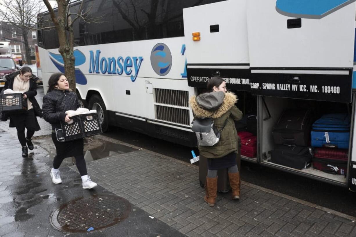 In this Dec. 30, 2019, photo, Jewish girls walk to a bus in the Crown Heights neighborhood of New York, for the trip to Monsey, N.Y. Monsey Trails commuter bus company offers daily service between Monsey, N.Y., and the New York City boroughs of Manhattan and Brooklyn. With the rapid expansion of Orthodox communities outside New York City has come civic sparring, and some fear the recent violence in the area may be an outgrowth of that conflict.