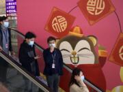 People wear face masks as they ride an escalator at the Hong Kong International Airport in Hong Kong, Tuesday, Jan. 21, 2020. Face masks sold out and temperature checks at airports and train stations became the new norm as China strove Tuesday to control the outbreak of a new coronavirus that has reached four other countries and territories and threatens to spread further during the Lunar New Year travel rush.