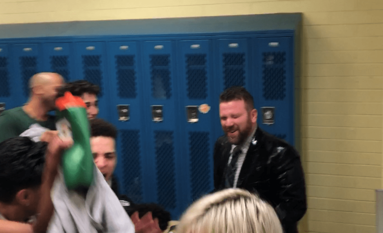 Evergreen boys basketball coach Brett Henry, right, reacts to being drenched with water as his players celebrate after a 56-44 win over Kelso on Friday in Kelso (Micah Rice/The Columbian)