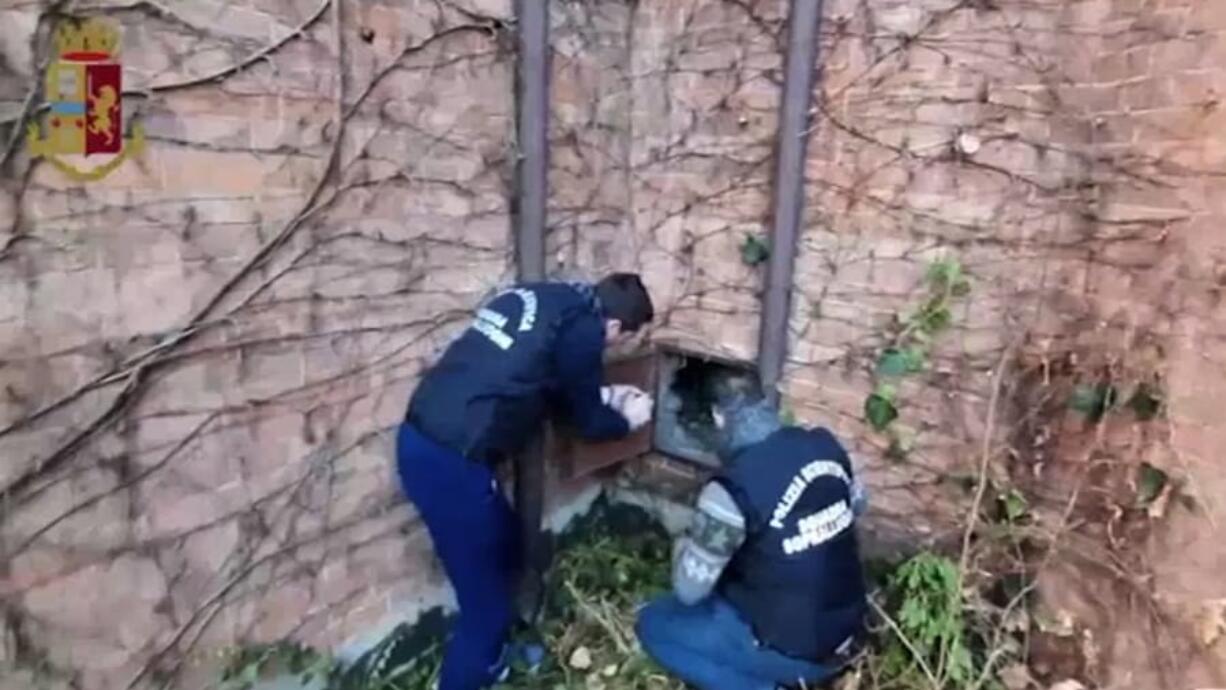 This image taken from a video distributed Wednesday, Dec. 11, 2019 by Italian police shows two forensic police officers approaching a metal panel in which a painting was found, in Piacenza, northern Italy. A gardener at the Ricci Oddi modern art gallery in the northern city of Piacenza told Italian state TV on Tuesday that he was clearing ivy from the gallery&#039;s walls when he noticed a metal panel in which he found a bag inside a space within the walls. When the bag was opened it contained a painting that might be Klimt&#039;s &quot;Portrait of a Lady,&quot; which disappeared from the gallery during renovations in February 1997.