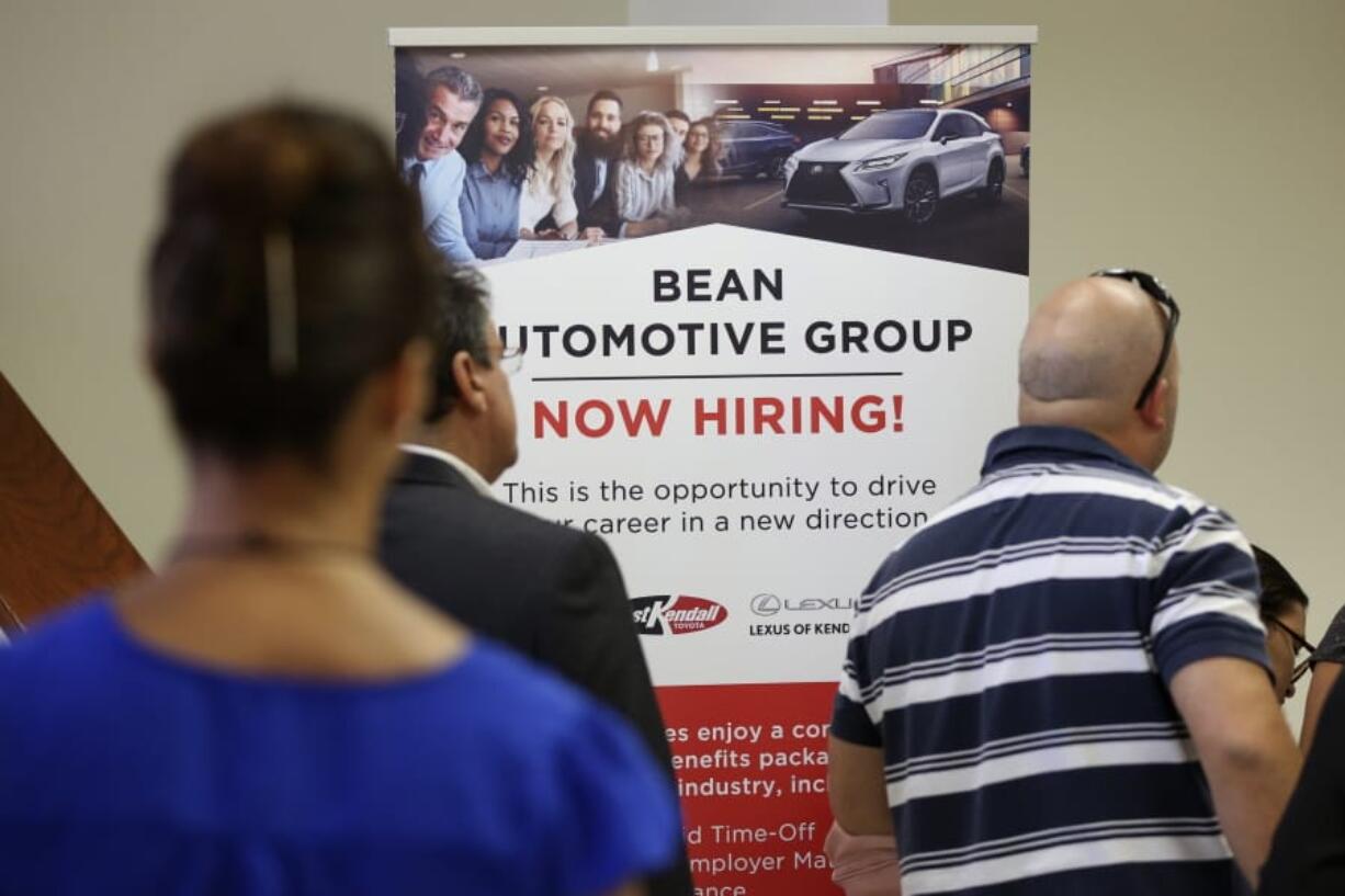 FILE - In this Sept. 18, 2019, file photo people stand in line to inquire about jobs available at the Bean Automotive Group during a job fair in Miami. On Friday, Jan. 10, 2020, the U.S. government issues the December jobs report.