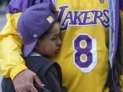 Eric Mascarenhas comforts his son Nicolas at a memorial for Kobe Bryant near Staples Center Monday, Jan. 27, 2020, in Los Angeles. Bryant, the 18-time NBA All-Star who won five championships and became one of the greatest basketball players of his generation during a 20-year career with the Los Angeles Lakers, died in a helicopter crash Sunday. (AP Photo/Ringo H.W.