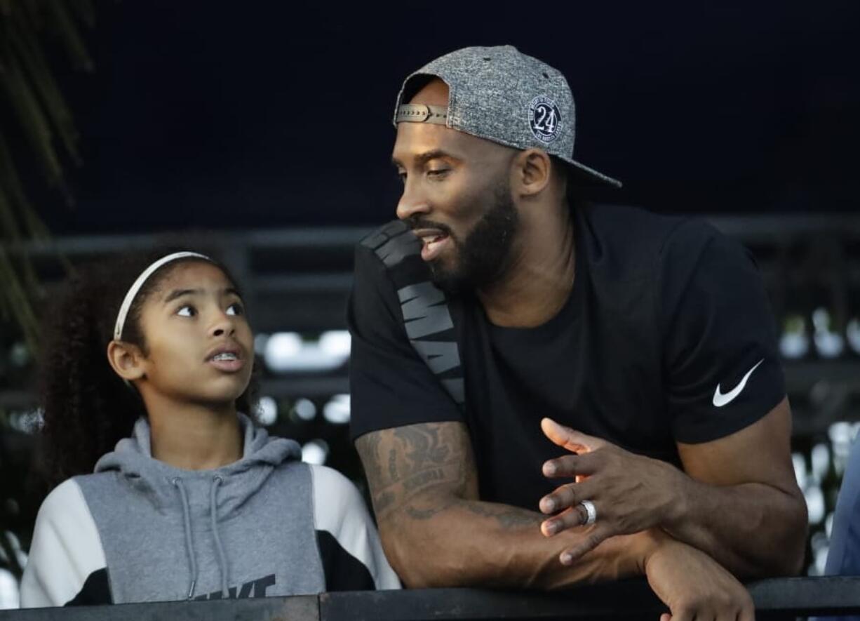 FILE - In this July 26, 2018 file photo former Los Angeles Laker Kobe Bryant and his daughter Gianna watch the U.S. national championships swimming meet in Irvine, Calif. Bryant, the 18-time NBA All-Star who won five championships and became one of the greatest basketball players of his generation during a 20-year career with the Los Angeles Lakers, died in a helicopter crash Sunday, Jan. 26, 2020. Gianna also died in the crash.