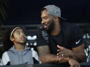 FILE - In this July 26, 2018 file photo former Los Angeles Laker Kobe Bryant and his daughter Gianna watch the U.S. national championships swimming meet in Irvine, Calif. Bryant, the 18-time NBA All-Star who won five championships and became one of the greatest basketball players of his generation during a 20-year career with the Los Angeles Lakers, died in a helicopter crash Sunday, Jan. 26, 2020. Gianna also died in the crash.