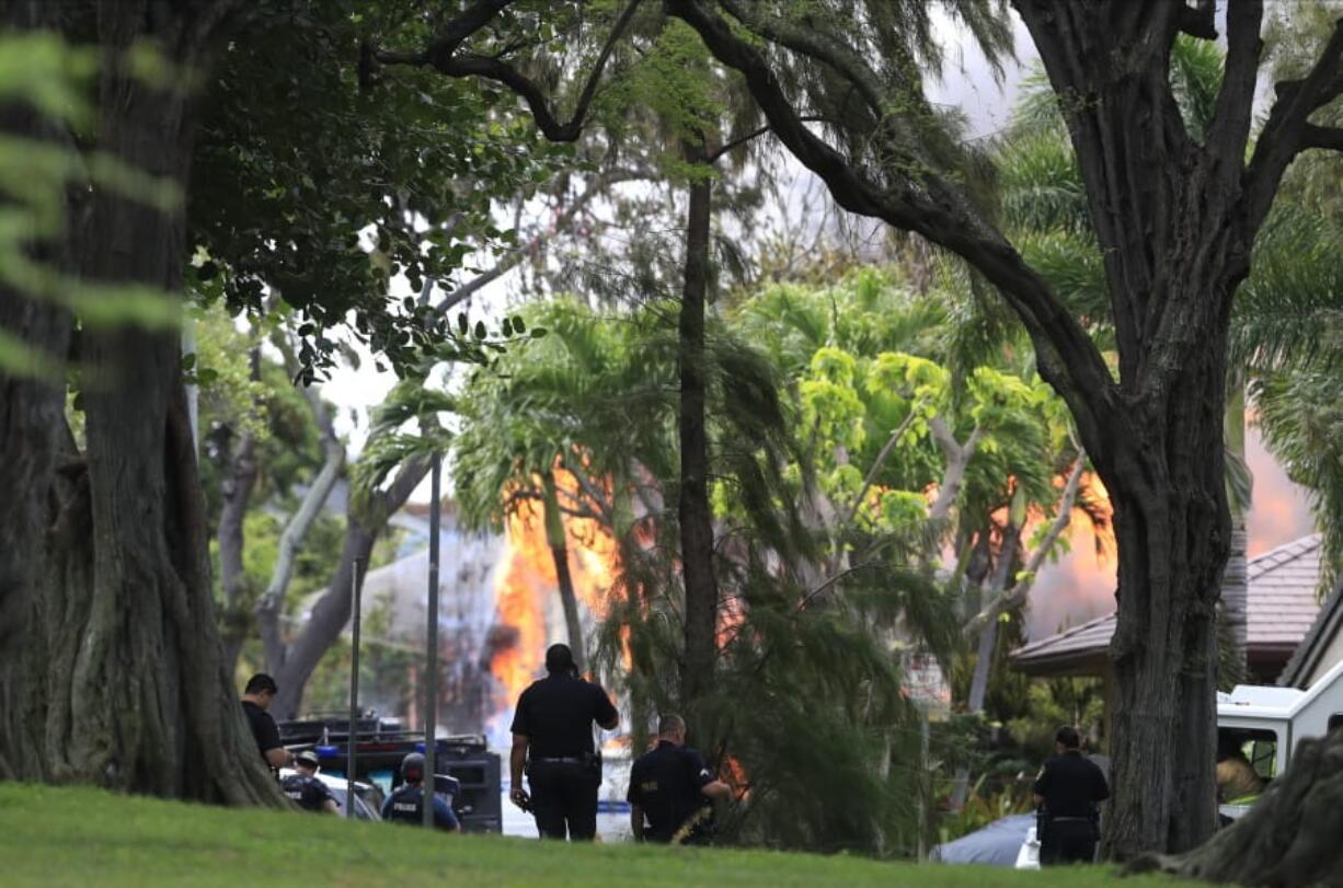 Honolulu police watch a house fire after a shooting and domestic incident at a residence on Hibiscus Road near Diamond Head on Sunday, Jan. 19, 2020, in Honolulu. Witnesses say at least two Honolulu police officers were shot and two civilians were injured. Moments after the shooting, the house was set on fire, possibly by the suspect.