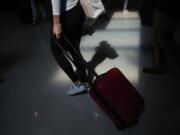 FILE - In this Nov. 27, 2019, file photo a traveler walks through the terminal at the Fort Lauderdale-Hollywood International Airport in Fort Lauderdale, Fla. Summer will be here soon, so it&#039;s a good time to start planning that vacation trip. Experts have plenty of tips for saving money on flights, lodging and other expenses.