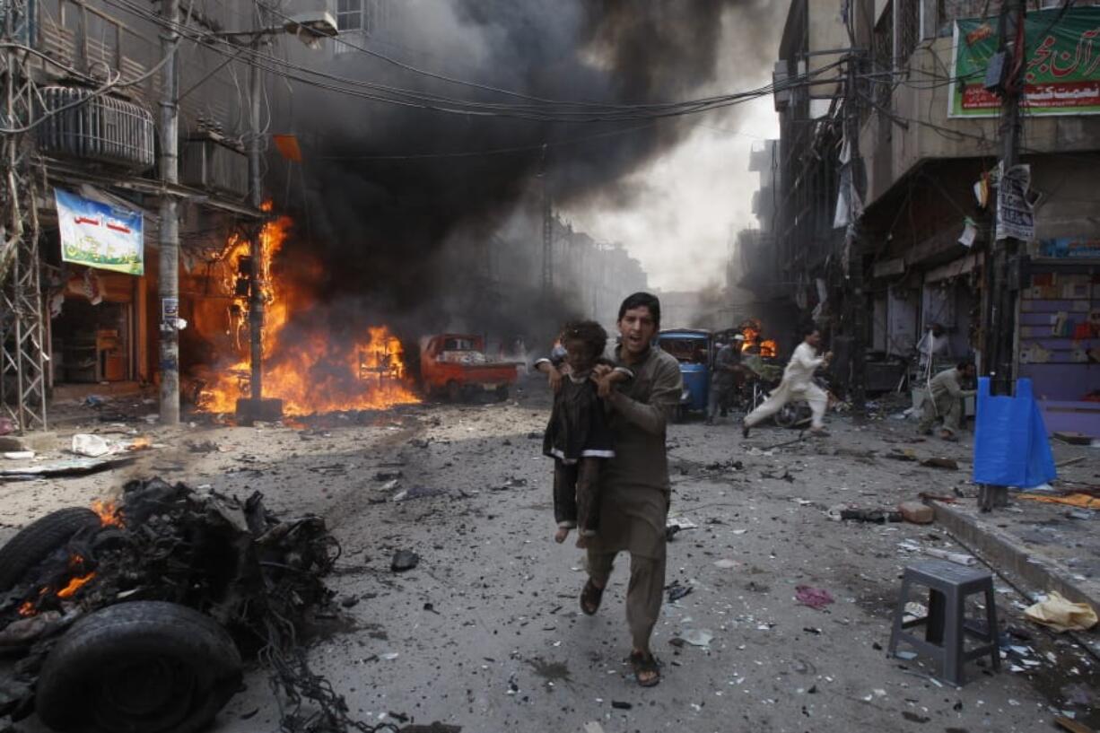 FILE - In this Sept. 29, 2013 file photo, a Pakistani man carrying a child rushes away from the site of a blast shortly after a car bomb exploded in Peshawar, Pakistan.  Terror attacks in Pakistan plummeted by more than 85% over the last decade. It&#039;s a welcome statistic for the country, but one that risks being overshadowed by international concern over its efforts to curb terror funding and lingering militant activity that could test any future peace agreement in Afghanistan.