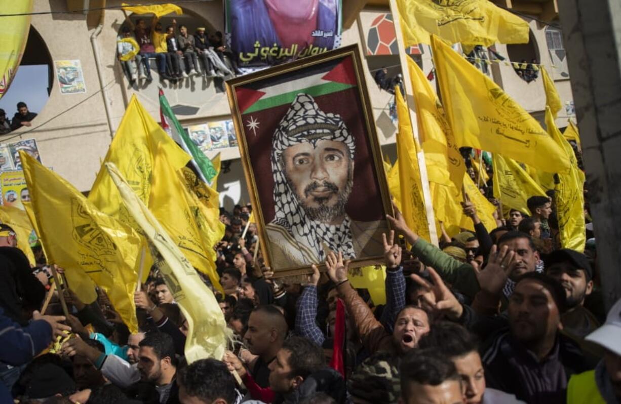 A Palestinian carries a picture of the late Palestinian leader Yasser Arafat, during a rally marking the 55th anniversary of the Fatah movement founding, in Gaza City, Wednesday, Jan. 1, 2020. Fatah is a secular Palestinian party and former guerrilla movement founded by Arafat, in Gaza City, Wednesday, Jan. 1, 2020.