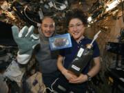 In this photo made available by U.S. astronaut Christina Koch via Twitter on Dec. 26, she and Italian astronaut Luca Parmitano pose for a photo with a cookie baked on the International Space Station.