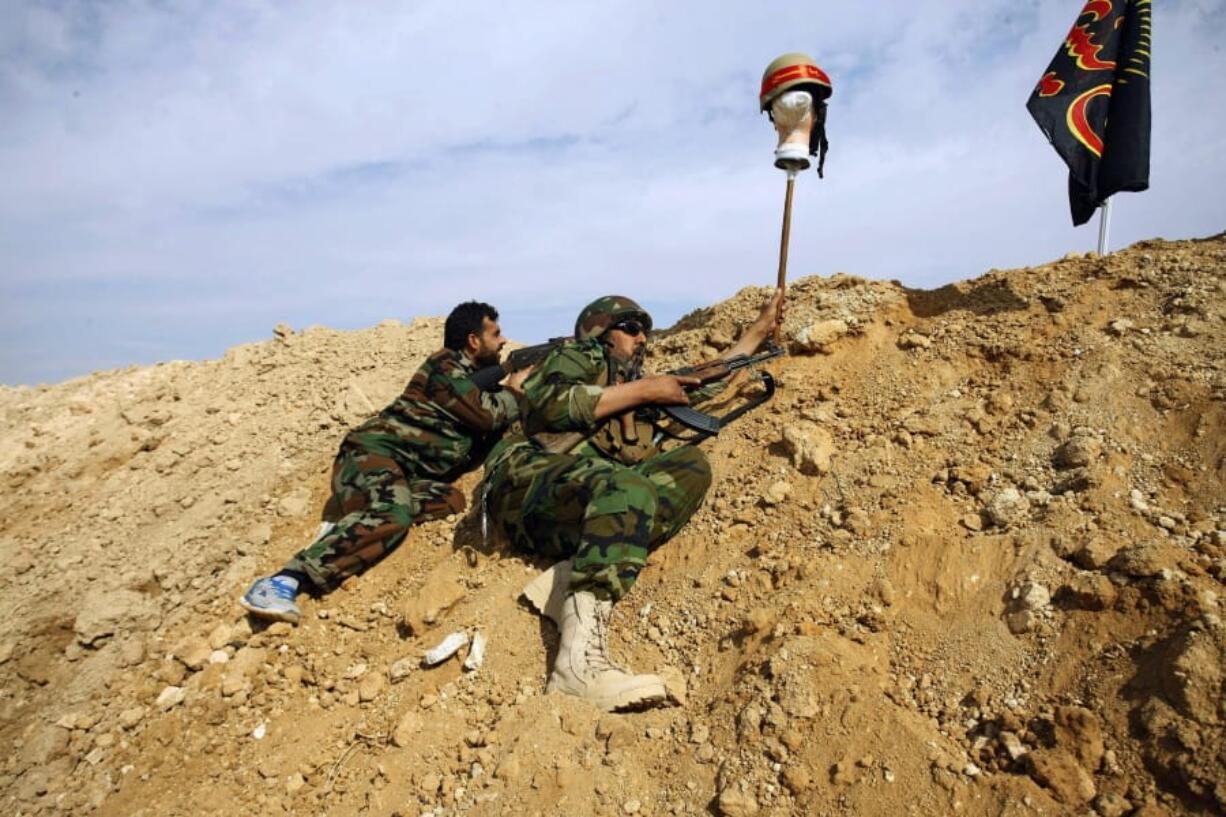 FILE - In this Nov. 22, 2013 file photo, Iraqi and Lebanese Shiite fighters from a group called the Hussein Brigade, loyal to Syria&#039;s President Bashar Assad, use a helmet to draw a sniper into view during clashes against the Sunni-dominated Free Syrian Army in the town of Hejeira, Syria, outside the capital Damascus. As Iran&#039;s frontman in Syria since 2011, Qassem Soleimani, Commander of Iran&#039;s Quds Force, brought in and organized thousands of Shiite militiamen from outside Syria to back President Bashar Assad&#039;s overstretched military, providing firepower and skills.