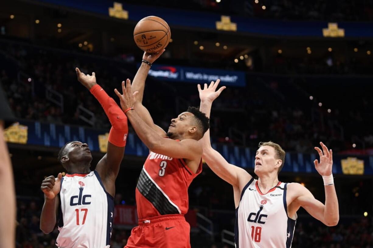 Portland Trail Blazers guard CJ McCollum (3) goes to the basket between Washington Wizards guard Isaac Bonga (17) and center Anzejs Pasecniks (18) during the first half of an NBA basketball game, Friday, Jan. 3, 2020, in Washington.