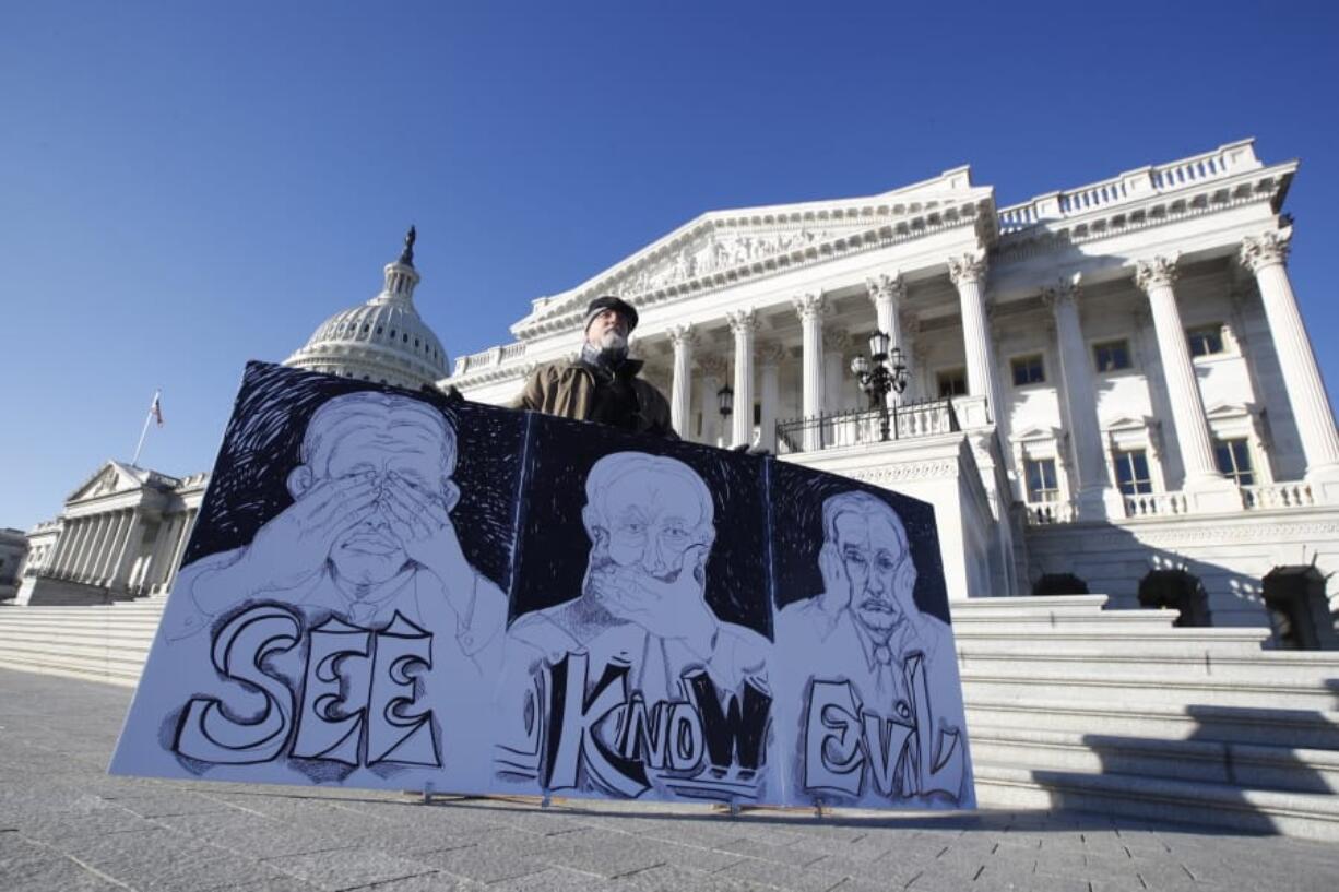 Stephen Parlato, of Bolder, Colo., displays his artwork depicting, &quot;the evil Republican senatorial judges&quot;, as he demonstrates outside the U.S. Capitol Wednesday, Jan. 22, 2020, in Washington.