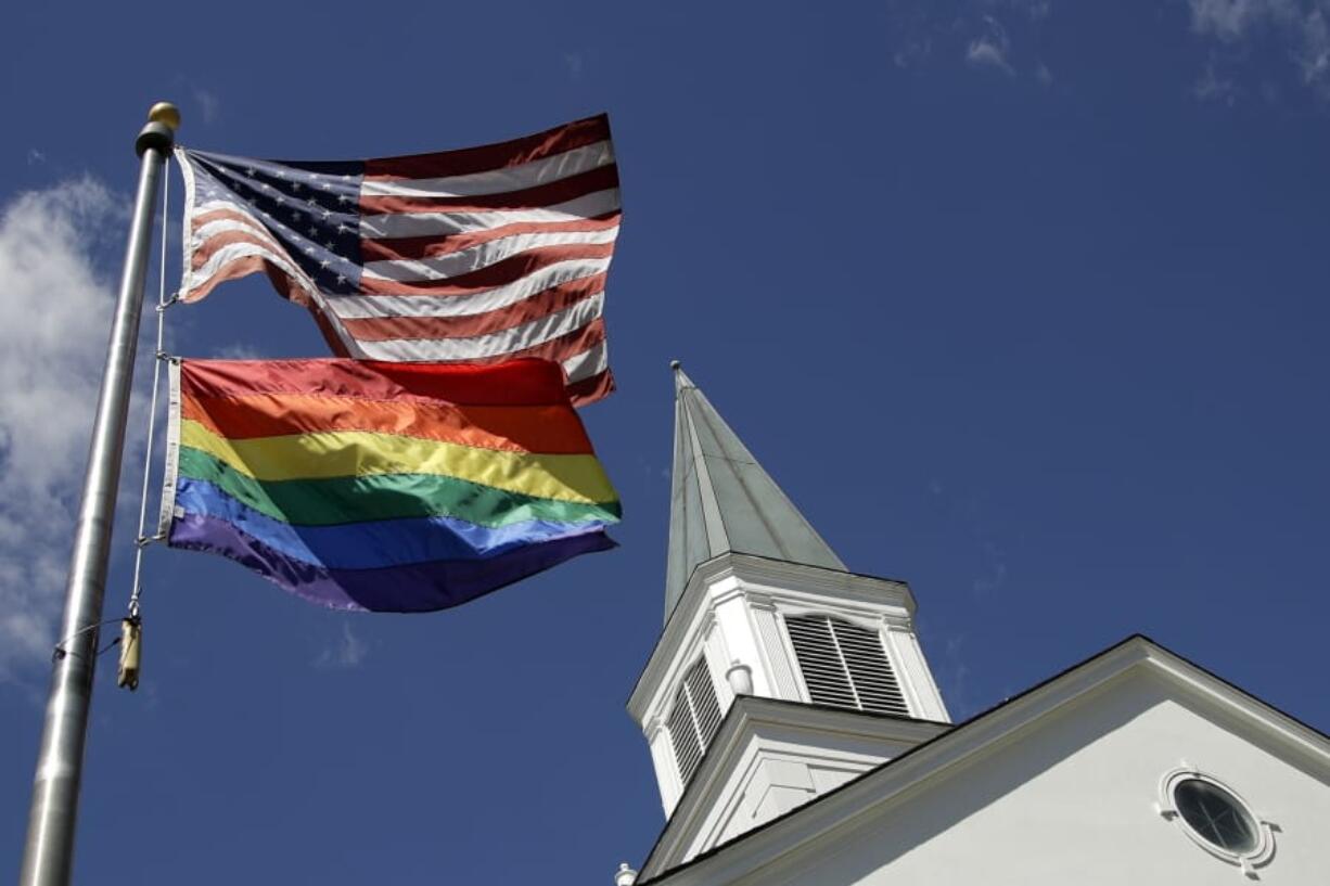 A gay pride rainbow flag flies along with the U.S. flag in front of the Asbury United Methodist Church on April 19, 2019, in Prairie Village, Kan.