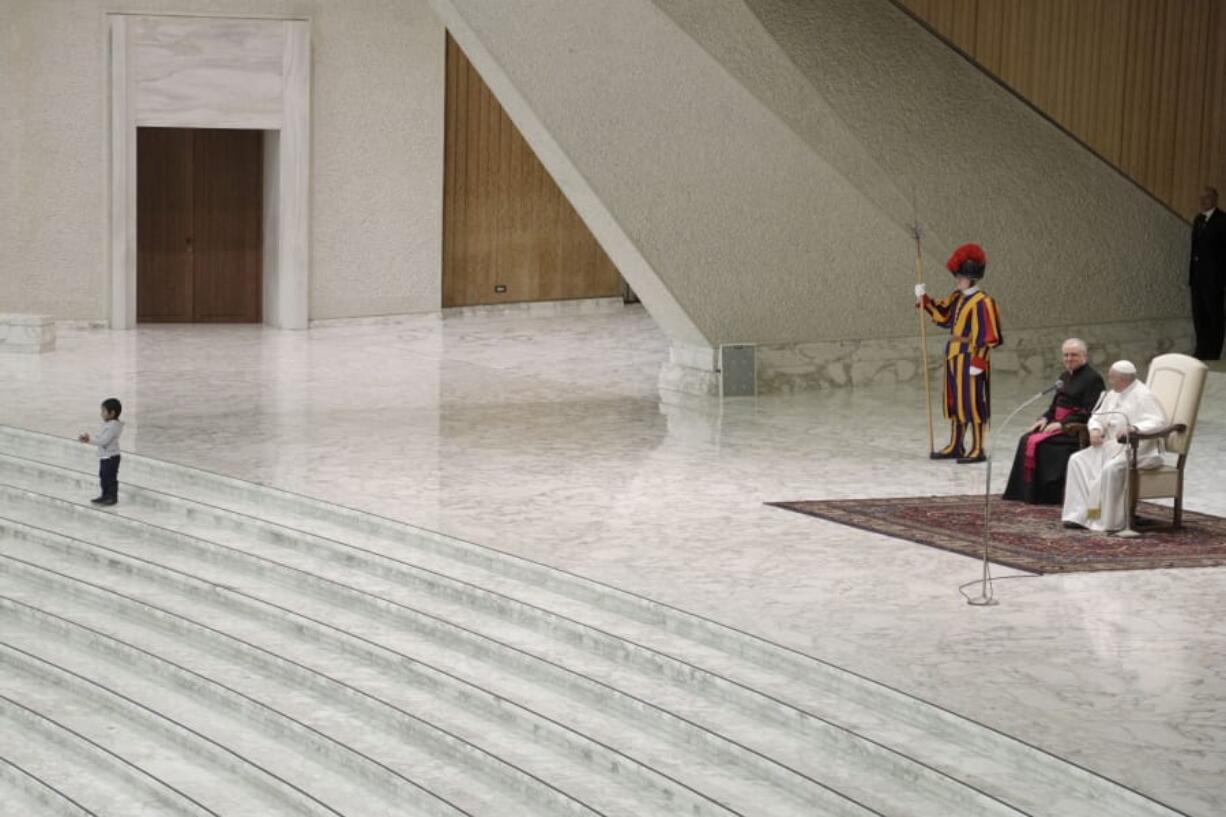 A child walks in front of Pope Francis during the weekly general audience in the Paul VI Hall at the Vatican, Wednesday, Jan. 22, 2020.