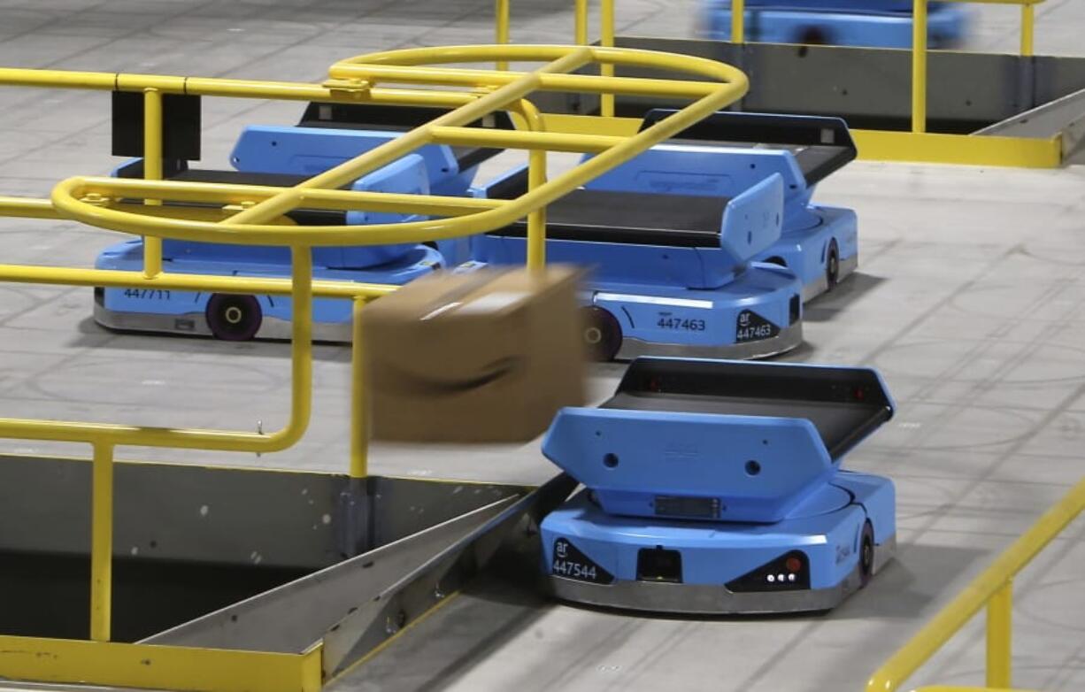 An Amazon robot sends a package down a chute, transporting packages from workers to chutes that are organized by ZIP code, at an Amazon warehouse facility in Goodyear, Ariz. (Photos by Ross D.