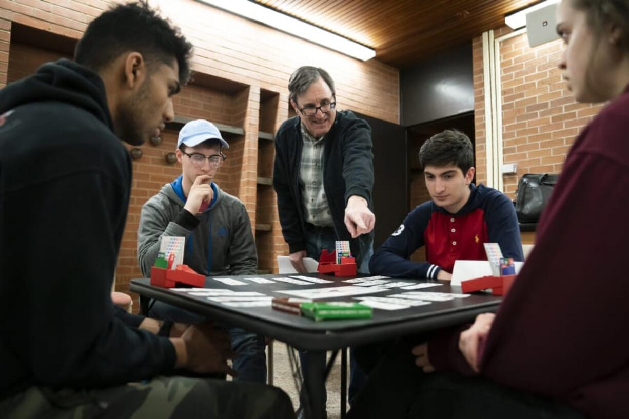 Paul Gutterman, standing at center, who is a tax professor at the University of Minnesota and an avid bridge player, gives a group of honors students guidance on their finished bridge game Feb. 10 during their Monday night gathering at Middlebrook Hall at the University of Minnesota in Minneapolis, Minn.