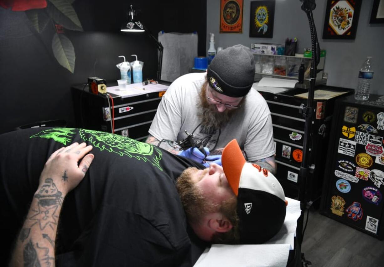 Tattoo artist Mike Kohler works on a custom tattoo on the arm of client Wyatt Hare of Baltimore during a recent session at Flesh Tattoo Company in Fallston.