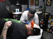 Tattoo artist Mike Kohler works on a custom tattoo on the arm of client Wyatt Hare of Baltimore during a recent session at Flesh Tattoo Company in Fallston.