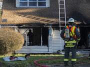 A firefighter, left, uses a flashlight to look over damage to a home in Salmon Creek after a fire gutted the residence on Friday morning, Feb. 21, 2020.