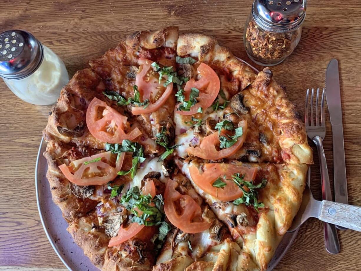 A custom pizza with red onions, mushrooms, fresh tomatoes, and fresh basil at Prairie Bar &amp; Grill.