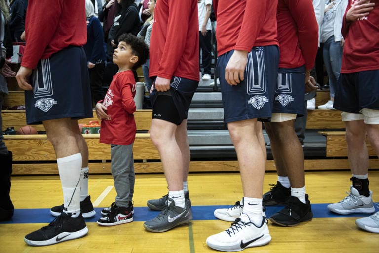 Cayson Bay, son of King’s Way assistant coach Kal Bay, stands with the team during the National Anthem prior to their game against La Center at La Center High School on Thursday night, Feb. 6, 2020.