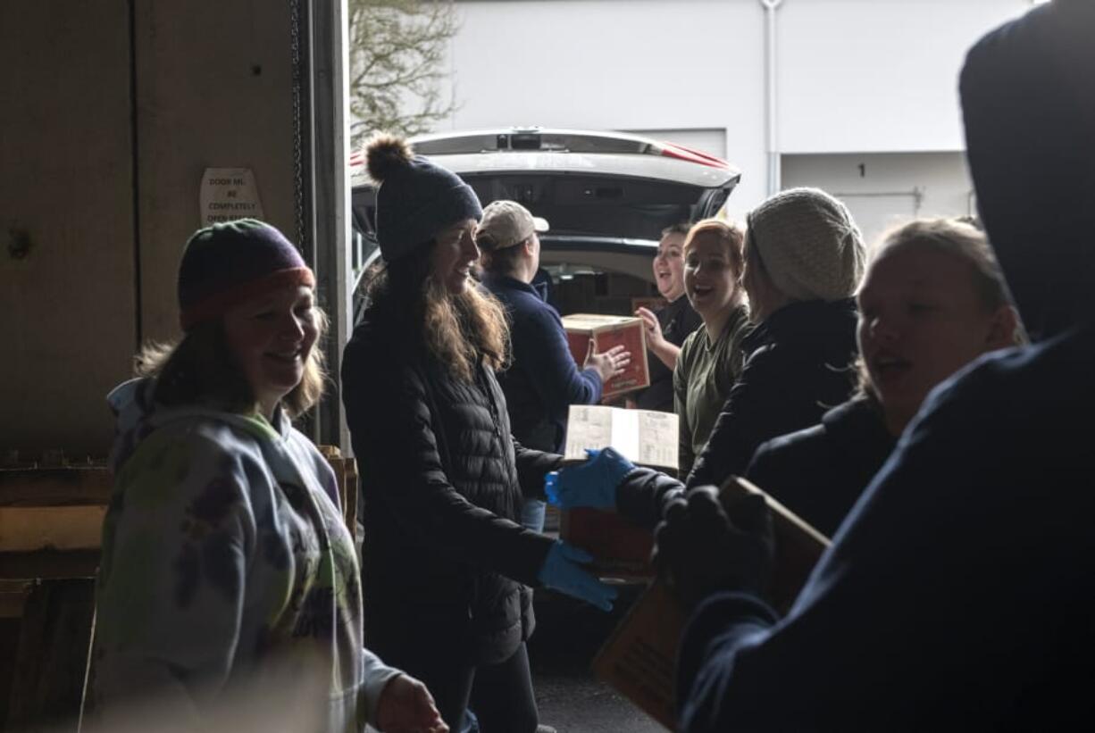 Volunteers work together to load Girl Scout Cookies into the trunk of a car Saturday morning.