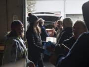 Volunteers work together to load Girl Scout Cookies into the trunk of a car Saturday morning.