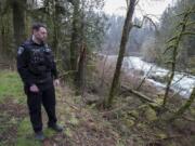 Washougal police Officer Francis Reagan pauses Thursday near the spot along the Washougal River where he rescued a woman from the water.