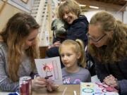 Engineering volunteer Caitlyn Bodda, from left, Agnes Himmelber, 5, Johnny Himmelber, 1, Marian Waggener and Meagan Himmelber, all of Ridgefield, test a circuit made from paper, copper tape and a small battery during Saturday&#039;s Rosie Revere Engineer Day at Pearson Field Education Center.