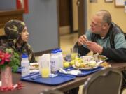 Donnie Rousey, 14, left, eats dinner with Mark Traxler, who is homeless and lives in Washougal, during Refuel Washougal&#039;s free weekly meal at the Washougal Community Center.