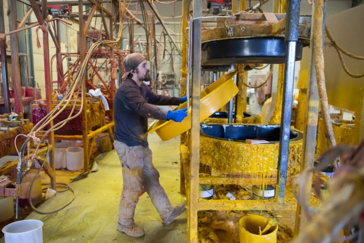 Fiberglass technician Brad Cherry takes one side of a life ring cabinet out of the mold to finish cooling at Cheyenne Manufacturing in Vancouver. The company specializes in storage cases for marine safety products, and is currently embarking on a fundraising project to build and install loaner life jacket cabinets in state parks.