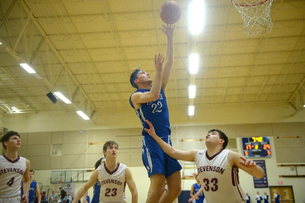 La Center senior Cedric Hubler (22) goes in for a layup over Stevenson&#039;s Bennett Wright during the first half of the 1A district semifinal game Tuesday at King&#039;s Way Christian High School. Hubler scored 11 points in the Wildcats&#039; 91-67 victory.