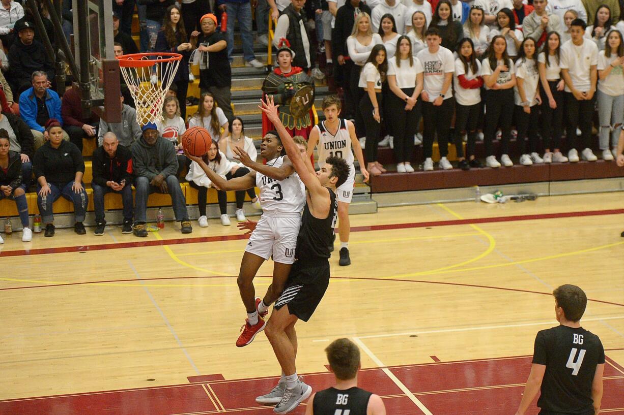 Union senior Ty McCullum gets two points around Battle Ground junior Kaden Perry during the 4A bi-district championship game at Prairie High School on Saturday, February 22, 2020. Union beat Battle Ground 82-57.