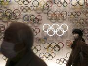 Two people wear masks as they visit the newly opened Japan Olympic Museum located near the New National Stadium, Sunday, Feb. 23, 2020, in Tokyo. (AP Photo/Jae C.