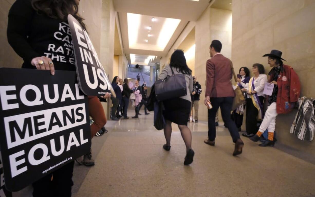 FILE - In this  Jan. 14, 2020, file photo, an Equal Rights Amendment supporters yell encouragement to two legislators as they walk down a hallway inside the state Capitol in Richmond, Va. A new poll from The Associated Press-NORC Center for Public Affairs Research shows that roughly three in four Americans support the gender equality amendment, which is now back before Congress with Virginia&#039;s ratification of the measure in January.