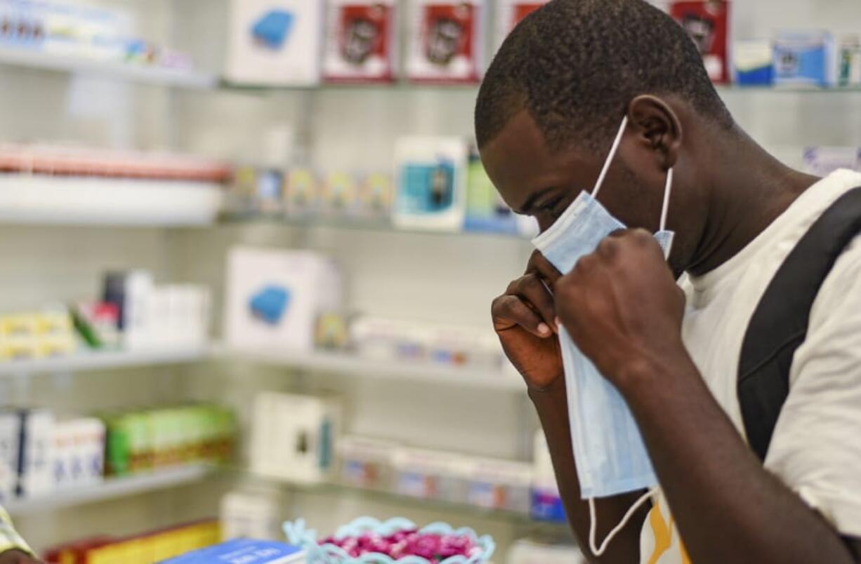 A man tries on a face mask at a pharmacy Thursday in Kitwe, Zambia.