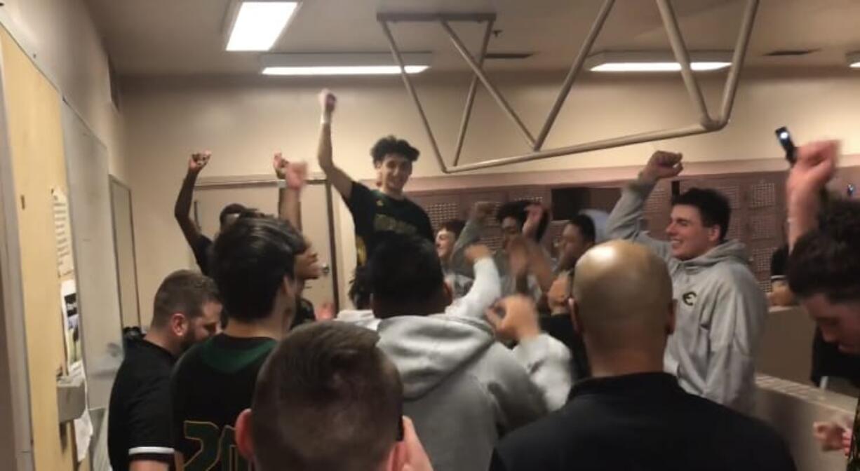 Izaac Romero (standing, facing camera) and the Evergreen Plainsmen celebrate their 75-70 overtime victory over Mount Tahoma on Thursday to advance to Saturday's bi-district title game.