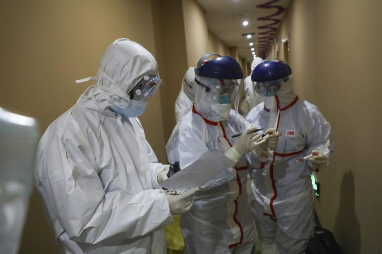 A medical worker in a protective suit writes on a tube after collecting a sample for nucleic acid tests from a suspected virus patient at a hotel being used to place people in medical isolation in Wuhan in central China&#039;s Hubei Province, Tuesday, Feb. 4, 2020. Hong Kong hospitals cut services as thousands of medical workers went on strike for a second day Tuesday to demand the border with mainland China be shut completely, as a new virus caused its first death in the semi-autonomous territory and authorities feared it was spreading locally.