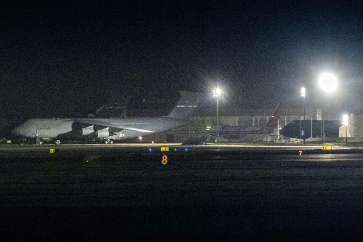 A charter flight transporting passengers from the quarantined Diamond Princess cruise ship moves behind military airplanes after it arrived at Travis Air Force Base in Fairfield, Calif., Sunday, Feb. 16, 2020.