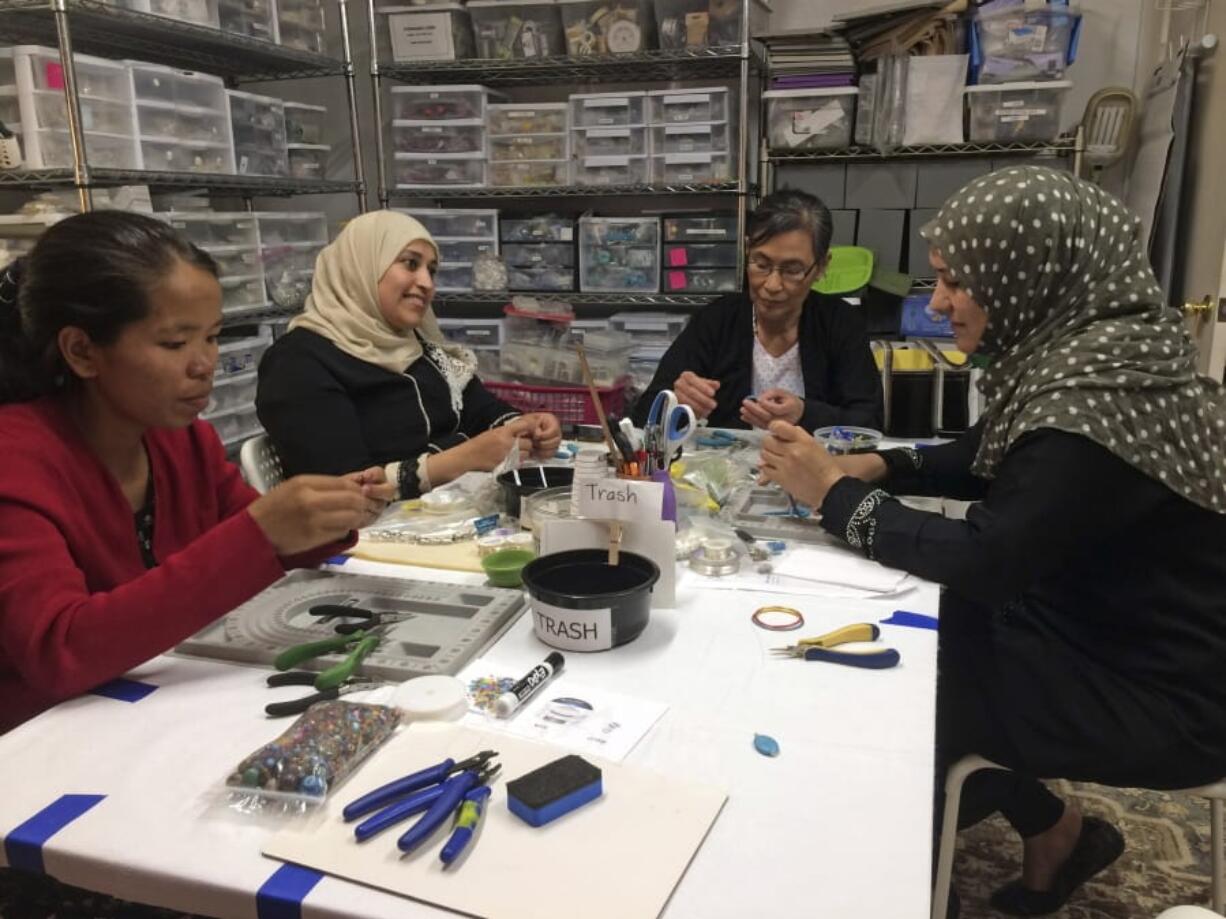 A Little Something participants Khei Hung from Burma, from left, Sabah Almobarak from Syria, Eh Gay Ju from Burma, and Mounira Kuru from Syria, work through frustration and creative challenges in their first lesson making wire-wrapped necklace pendants May 15 in Aurora, Colo. A Little Something helps women refugees turn their crafts into dollars. Around the world there are organizations that use crafting and the arts as tools to help refugees build community and learn new skills. (Sharon L.