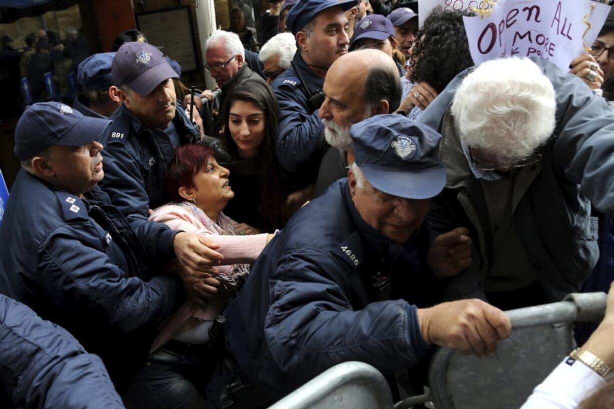 Protesters break the police barriers  as they demonstrate against the closing of a crossing point straddling a United Nations-controlled buffer zone in divided capital Nicosia, Cyprus, Saturday, Feb. 29, 2020. Around 200 people gathered at the Ledra Street crossing point to voice their opposition to its closing. The Cyprus government said it closed the Ledra Street crossing point along with three others to help with efforts to prevent the possible spread of a new COVID-19 virus either to the breakaway, Turkish Cypriot north or the internationally recognized, Greek Cypriot south.