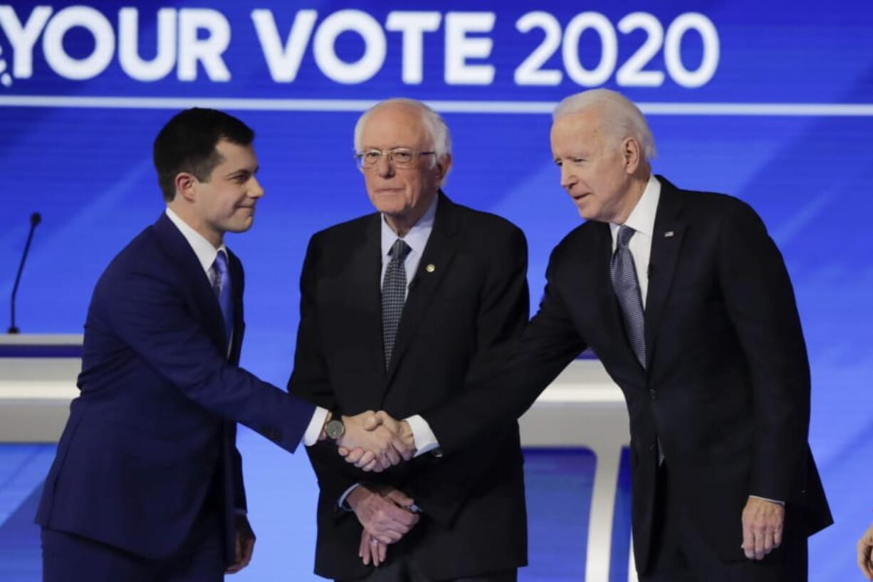 From left, Democratic presidential candidates former South Bend Mayor Pete Buttigieg, shakes hands with former Vice President Joe Biden as Sen. Bernie Sanders, I-Vt., watches Friday, Feb. 7, 2020, before the start of a Democratic presidential primary debate hosted by ABC News, Apple News, and WMUR-TV at Saint Anselm College in Manchester, N.H.