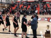 The Woodland boys basketball team receives the 2A district tournament runner-up trophy from tournament director Rob Blackman after a 63-28 loss to Tumwater in the championship game Friday at Battle Ground High School.